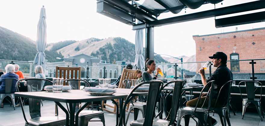 Warfield Distillery rooftop bar guests sip drinks beneath the covered seating area in downtown Ketchum, Idaho