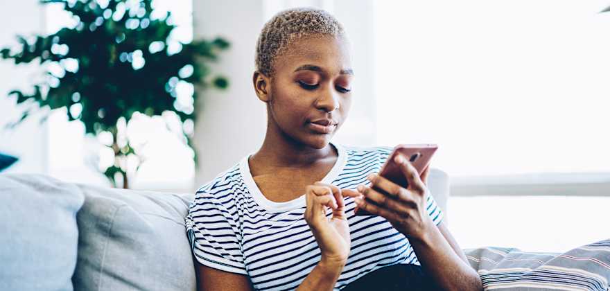 A woman uses her cell phone on the couch.