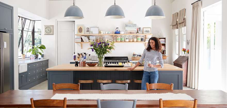 A woman stands in her bright modern kitchen.