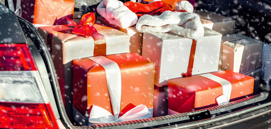 Red and white wrapped presents in the open trunk of a car