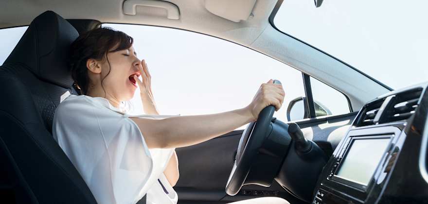 A woman yawns while driving.