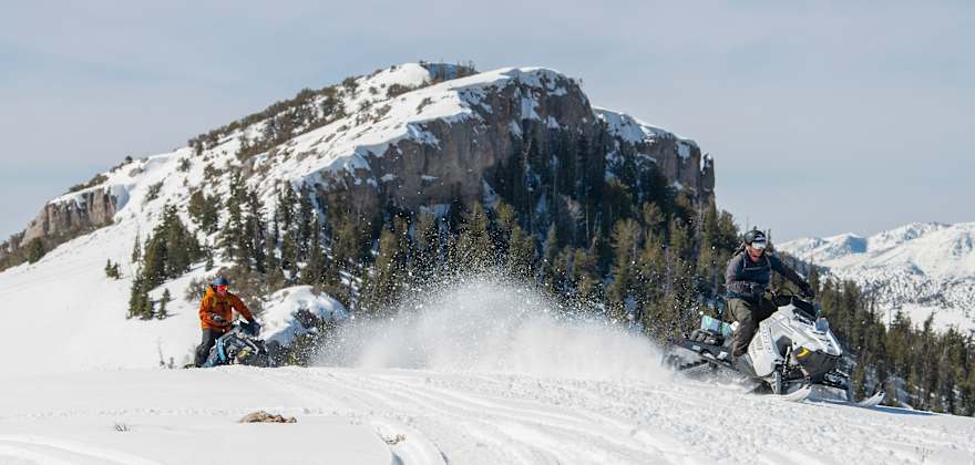 two people on snomobiles carve through fresh poweder in Ely, Nevada.