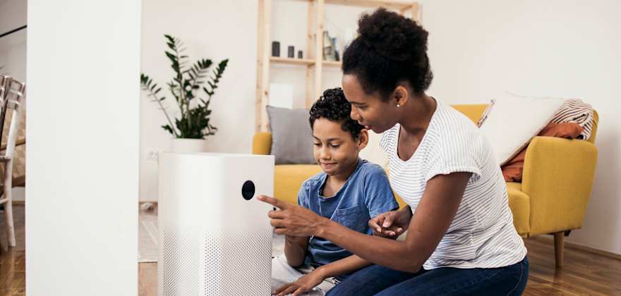 A mother and son turn on their air purifier in their living room.