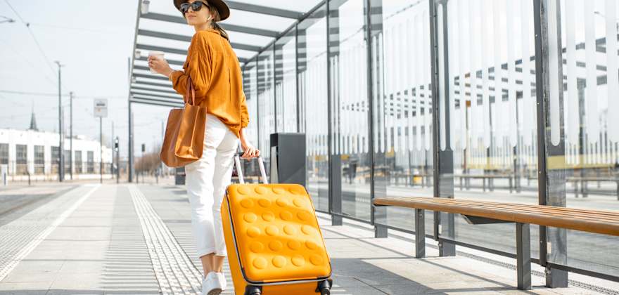 A woman walks with her luggage at a train station outside an airport.