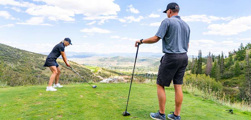A couple play golf at Park City, Utah on a partly cloudy day.