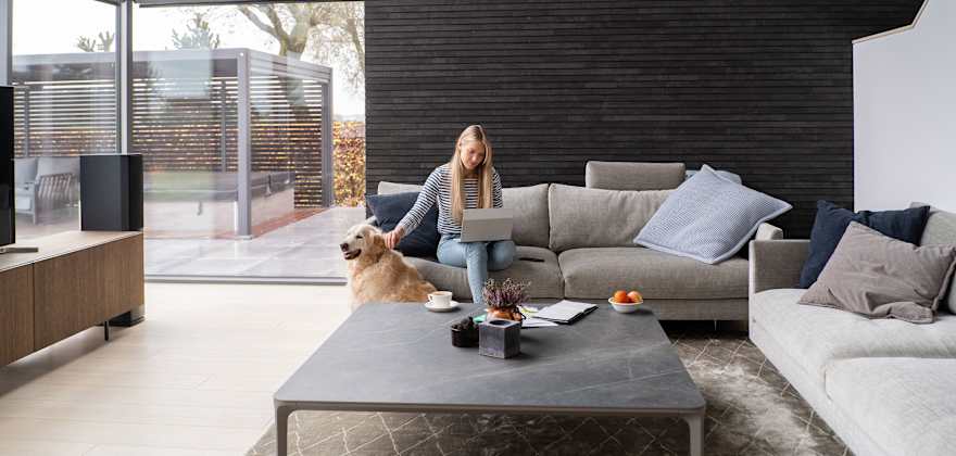 A woman sits on her couch with her dog in a modern home.