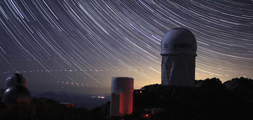 A time-lapse image shows stars in the night sky at an observatory.