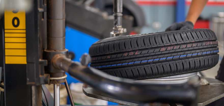 A mechanic mounts a tire on a rotation machine in a garage.