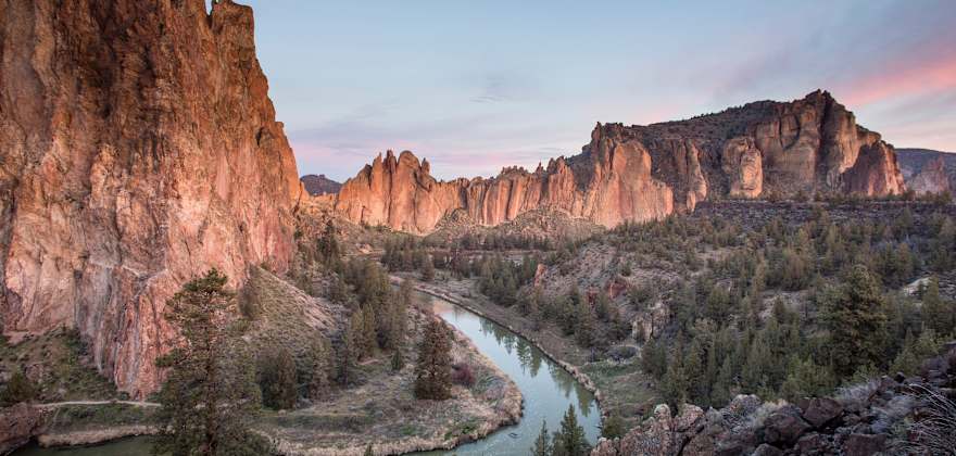 A river winds through dramatic red rock cliffs at sunset