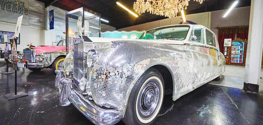 a Rolls Royce covered in glittery gems under a chandelier