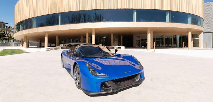 a blue Dallara Stradale sports car parked in front of the Dallara Academy