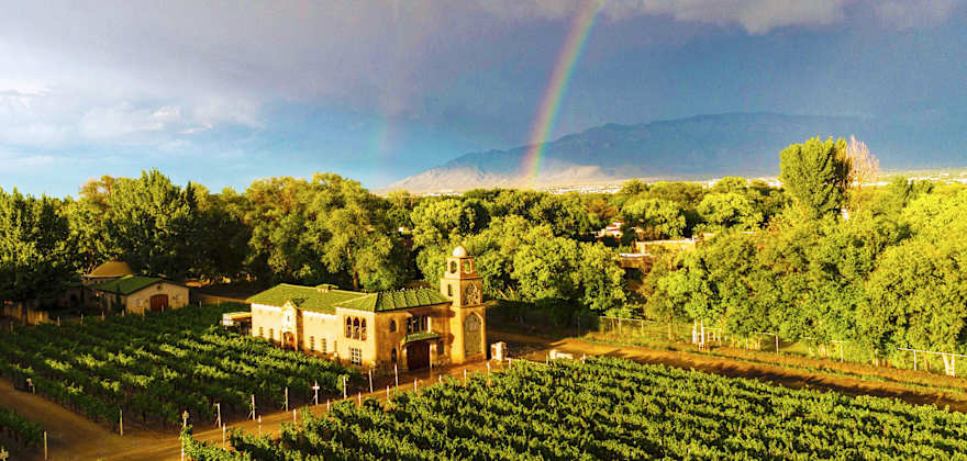 a rainbow over a vineyard and winery building