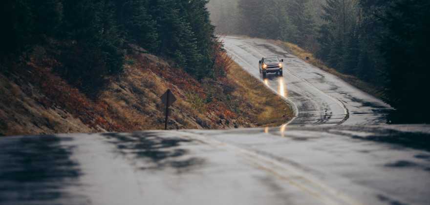 A truck drives on a wet road in the rain.