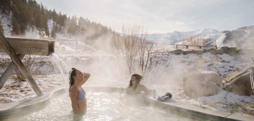 Friends soak at Astoria Hot Springs Park in Wyoming on a winter day.