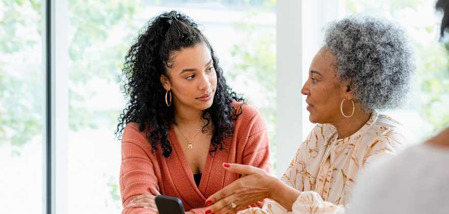 A mother and daughter look at the mom's phone for scam messages.