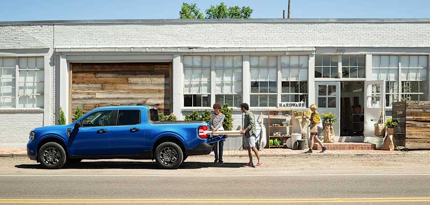 A couple load wood into the back of a 2025 Ford Maverick XLT.