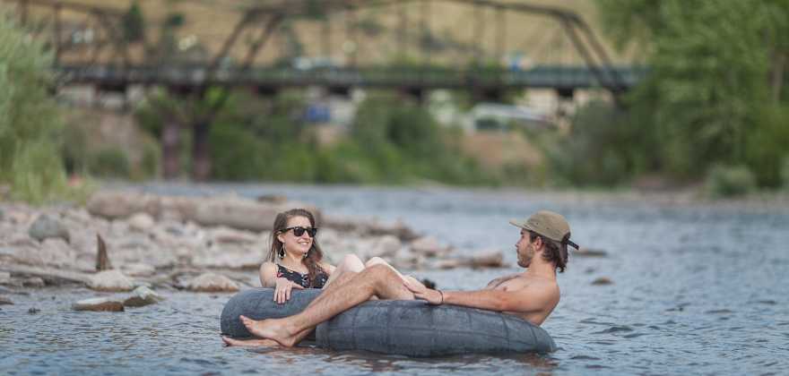 a woman and a man float in inner tubes on the Clark River in Missoula, Montana