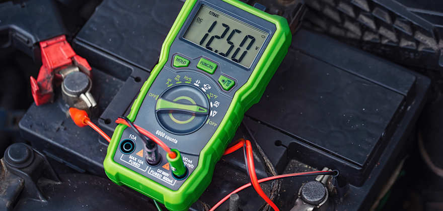 A multimeter plugged into a car's battery.
