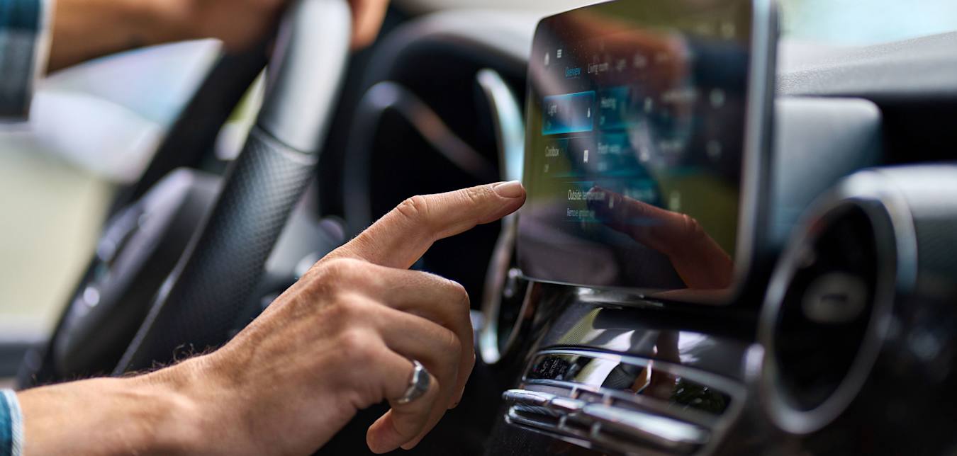 A driver uses the infotainment screen in the car while driving.