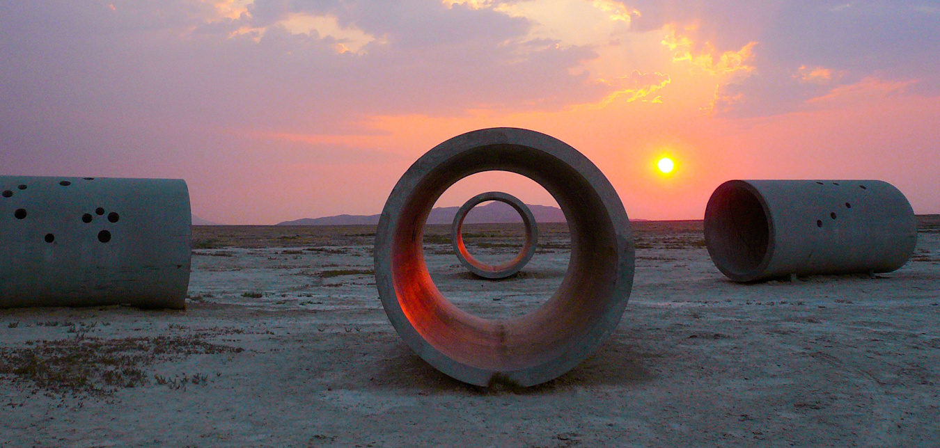 Sculptural concrete-and-steel tubes in the Utah desert at sunset.