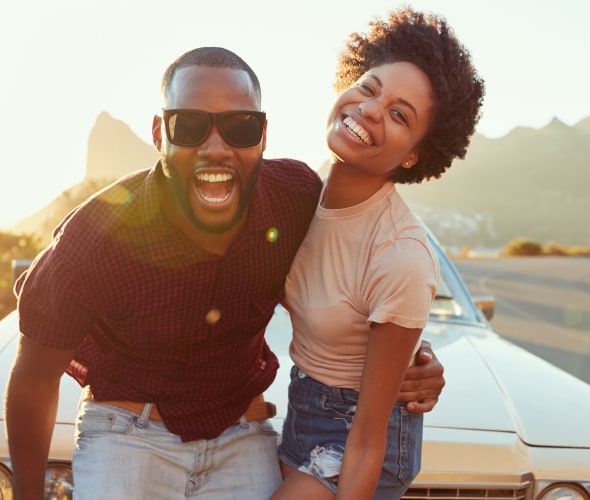 African American couple stand in front of a classic car along the bluffs at sunset