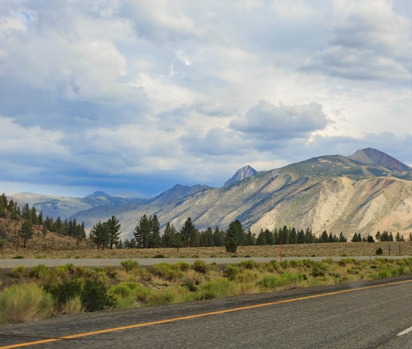 The pavement of Highway 395 in Northern California stretches towards the mountains in the distance.