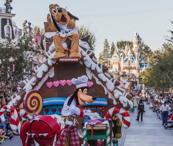 a picture of Goofy on a gingerbread house float during the daily Christmas parade at Disneyland