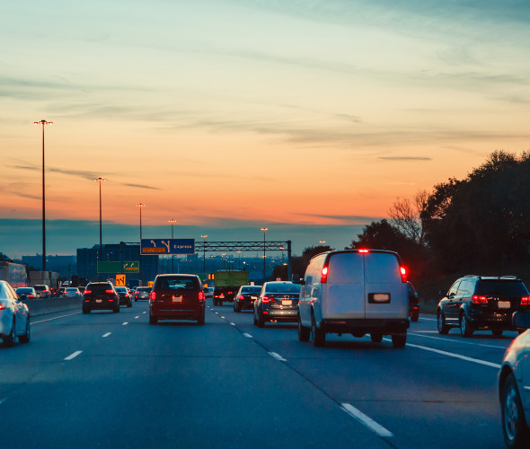 Cars on the freeway at night with an orange sunset in the background, photo