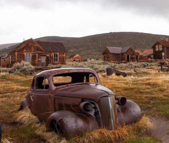 Rusted car and abandoned buildings in the ghost town of Bodie, California.