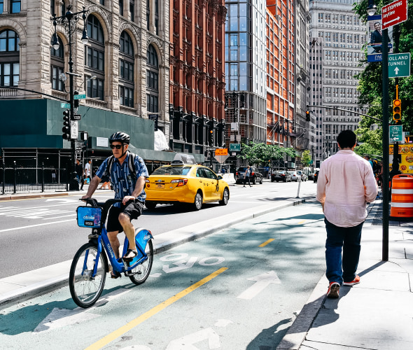 A man rides a shared bike on a protected bike lane in New York City.
