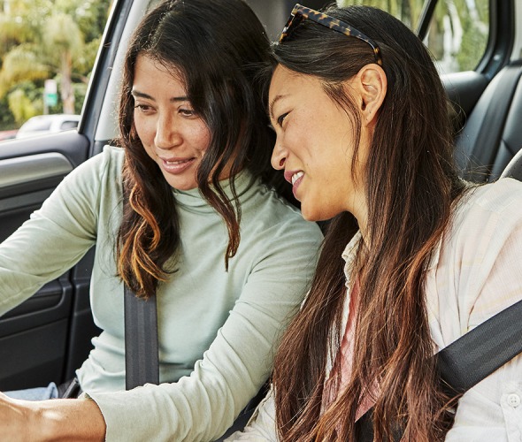 two women in parked car looking at mobile device