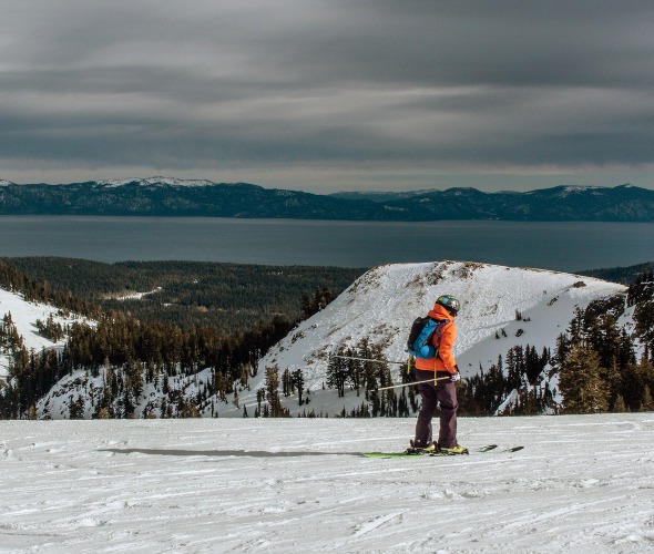 two skiers riding downhill at Alpine Meadows resort with Lake Tahoe in the background, image