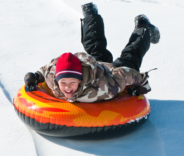 boy having fun on an inner tube in the snow, Sierra Nevada