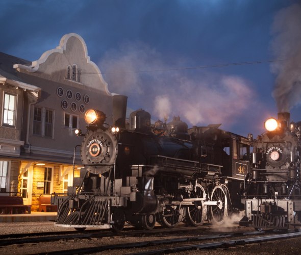 two steam train engines at the East Ely train depot at night, image