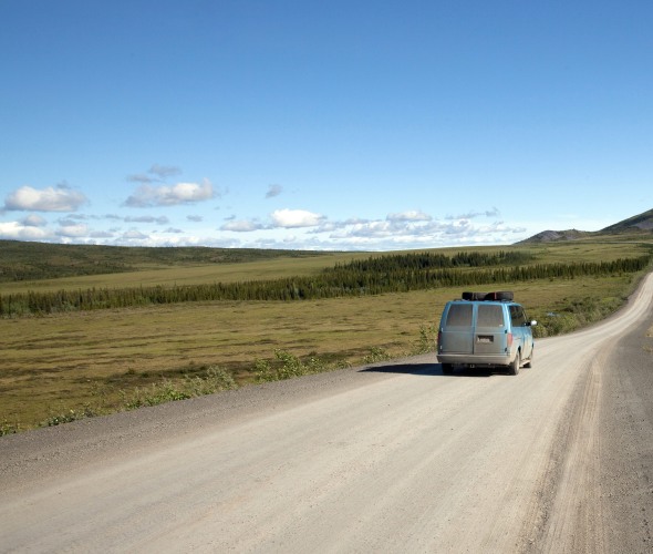 picture of a van driving along a stretch of the Dempster Highway above the Arctic Circle in northern Yukon.