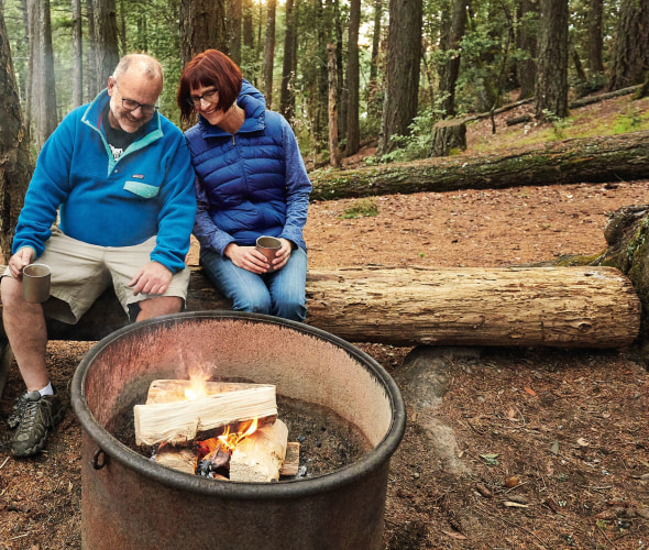 Peter and Nancy Fish, surrounded by redwoods, cozy up by their campsite fire pit in late afternoon at Pantoll campground at California's Mount Tamalpais, picture
