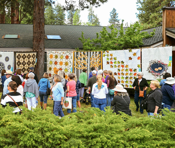 small crowd admires the custom quilts on display at Sisters Outdoor Quilt Show in Sisters, Oregon, picture