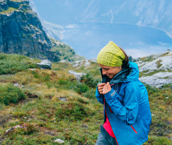 A hiker puts on a rain coat near a fjord in Norway.