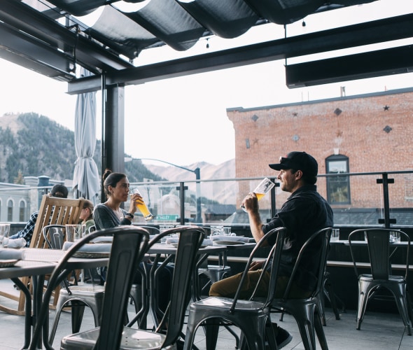 Warfield Distillery rooftop bar guests sip drinks beneath the covered seating area in downtown Ketchum, Idaho