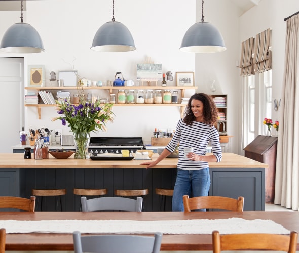 A woman stands in her bright modern kitchen.