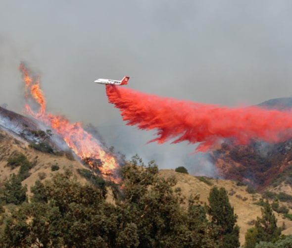 An airplane drops fire retardant on a wildifre in California.