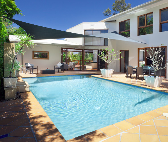 A beautiful pool in the backyard of a modern white home.