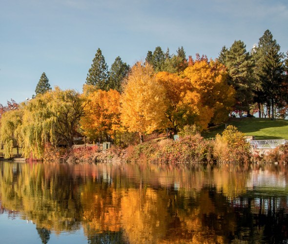 The Great Northern Clocktower and trees with yellow and orange leaves reflect off the Spokane River.