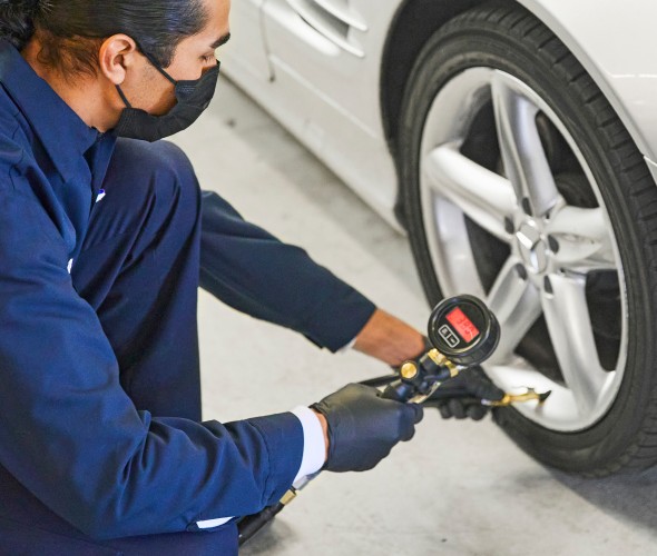 AAA Repair Center mechanic uses a tire pressure gauage to check a car's tire pressure.