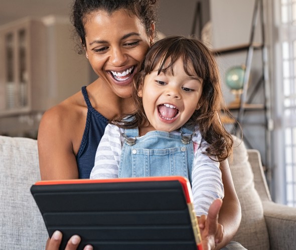 A mom and her child play together on a tablet.