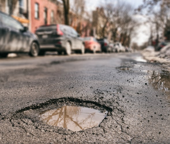 A pothole reflects the sky on a winter road.