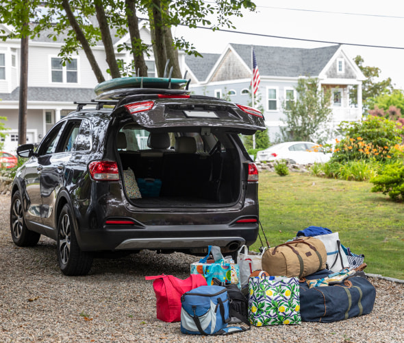Bags are piled up behind an SUV to be loaded into the car before a road trip.