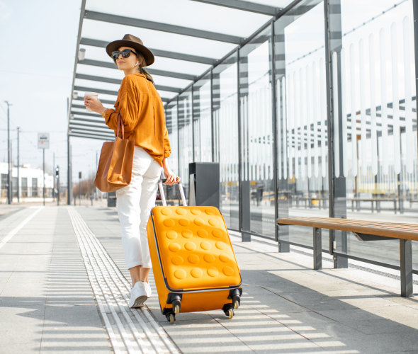 A woman walks with her luggage at a train station outside an airport.