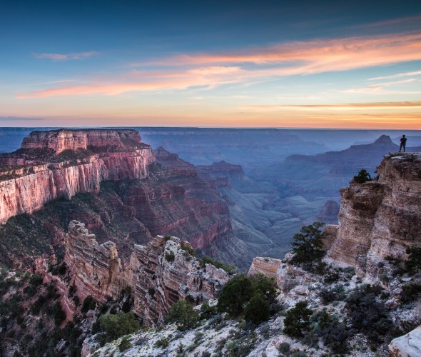 a hiker watches the sunset at the North Rim of the Grand Canyon.