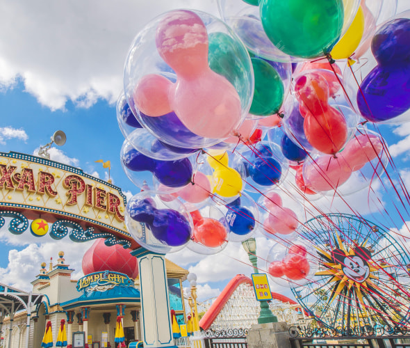 colorful Mickey Mouse balloons float in front of the pixar pier sign at california adventure.